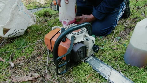 A man refills a chainsaw to work in the forest. Petrol Chainsaw. Stock Footage 140223765