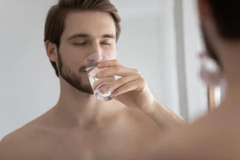 Man reflecting in mirror while drinks clean still mineral water Stock Photos