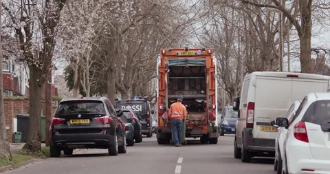 Man in reflective jacket placing a green recycling bin to a dust cart in street 库存影片 150044959