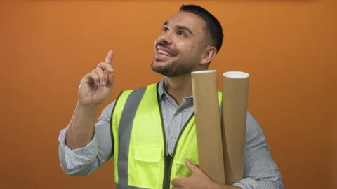 Man in reflective vest holding rolled blueprint points finger to ceiling sm.. Stock Footage 315539643