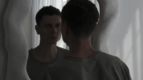 Man reflects on his identity in the mirror. Concept of self-exploration and Stock Footage 310937698