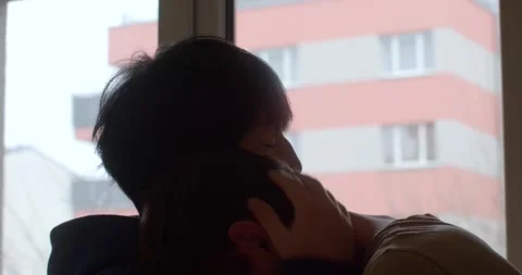 A man reflects by a window, connecting emotionally while kissing a woman Stock Footage 311815745