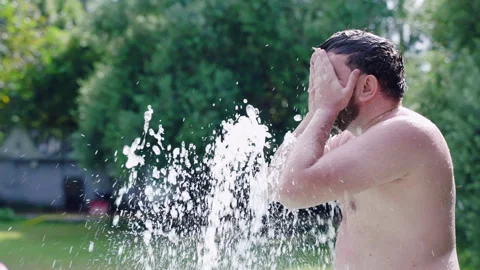 Man refreshing face with cold pool waterfall, relax in swimming pool on summer Stock Footage 261086927