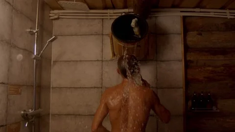 Man refreshing himself anfter hot sauna with cold water from wooden bucket Stock Footage 221940452