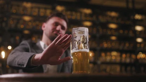A man refuses to drink beer by extending his hand and showing a stop sign. The Video stock 278469765