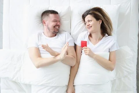 Man refuses to use condoms while lying in bed with woman Foto stock