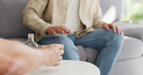 Man refusing alcohol at home, stop gesture near bottle on table, stay sober Stock Footage 327262352