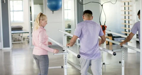 Man in rehabilitation using parallel bars with therapist in physical therapy Stock-Footage 300148144