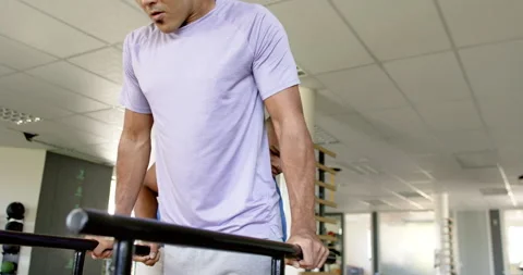 Man in rehabilitation, using parallel bars with therapist's assistance in gym Stock-Footage 300148228