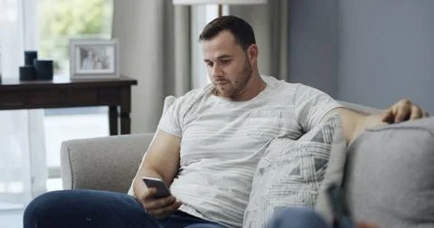 Man, relax and reading on couch with phone, text message notification and w.. Stock Photos