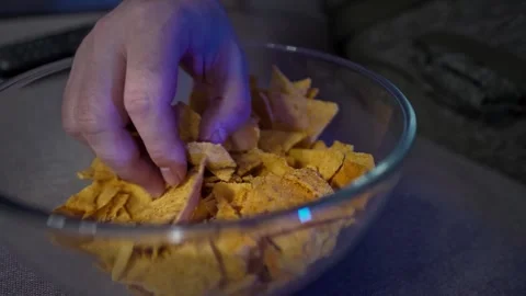 A man relaxes on the couch, snacking on chips and binge-watching his favorite Video stock 300311531