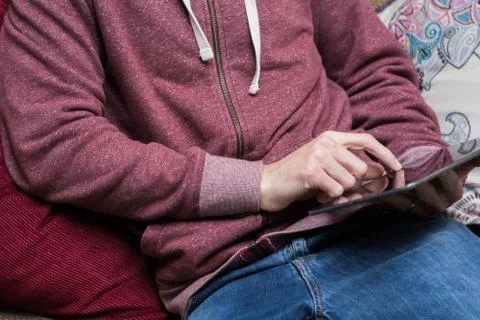 A man relaxes at home using a tablet on the sofa Stock Photos