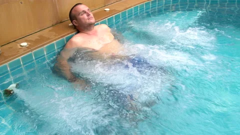 A man relaxes in the Jacuzzi Stock Footage 91829596