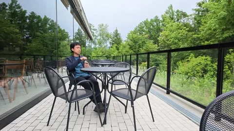 Man relaxes at outdoor table, sipping drink Stock Footage 340435513
