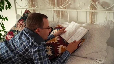 Man relaxes reading a book while lying on the couch Video stock 161393243