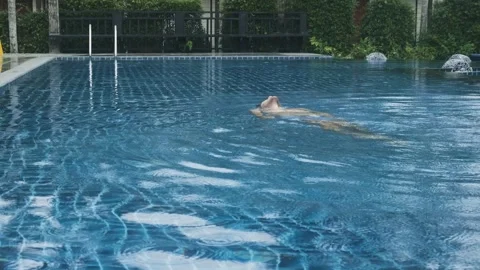 Man relaxing and floating on his back in tropical resort swimming pool 動画素材 288111530