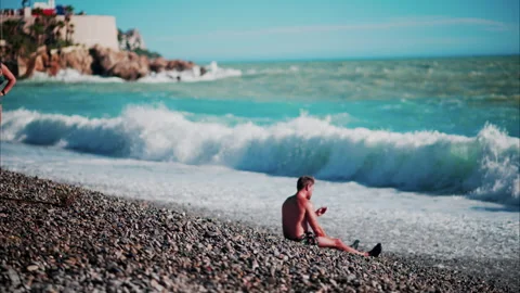 Man relaxing on the beach while Waves hitting the shore in Cannes, France Stock Footage 289979433