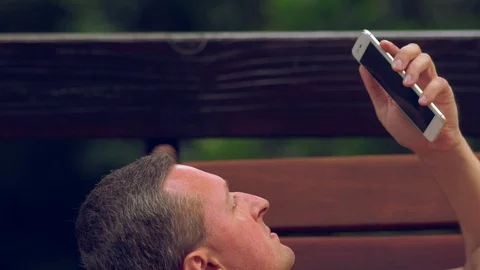 Man relaxing on a bench reading on a mobile Video stock 112155487