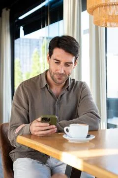 Man relaxing in cafe browsing smartphone Stock Photos