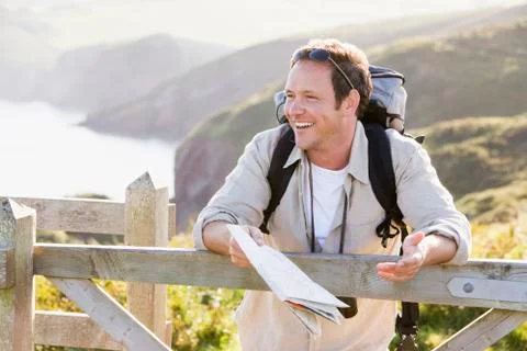 Man relaxing on cliffside path holding map and laughing Stock Photos