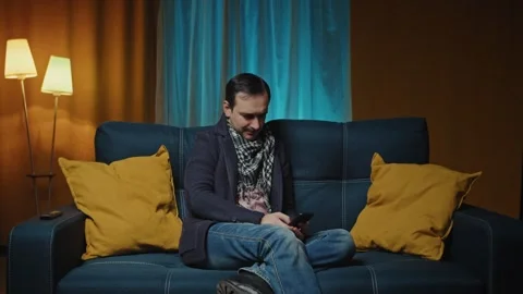 Man relaxing on comfortable couch, using mobile application in living room Stock Footage 247555472