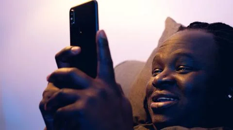 Man relaxing in the couch and browsing dating site on his smartphone Stock Photos