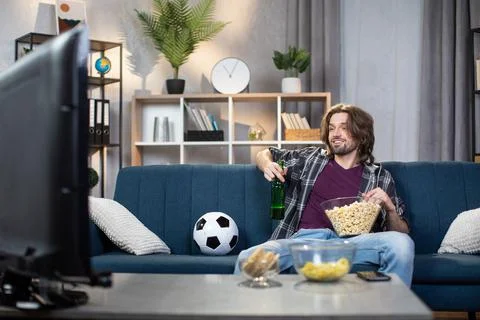 Man relaxing on couch while watching football game Stock Photos