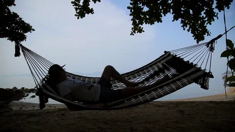 Man Relaxing In Hammock On The Beach Stock Footage 75464822