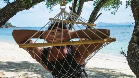 Man Relaxing in a Hammock with Ocean View Stock Footage 302412683