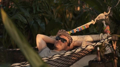 Man relaxing in a hammock on a sunset background. Vacation concept. Stock Footage 123781145