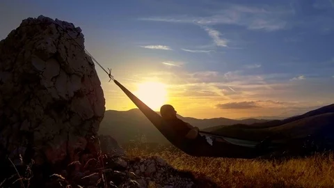 Man relaxing in hammock at sunset in the mountains Stock Footage 80114730