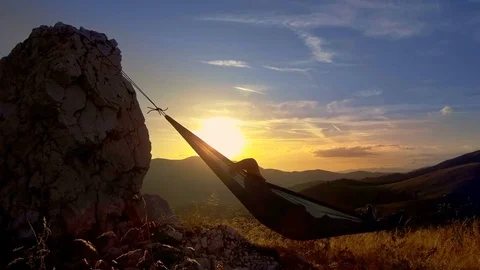 Man relaxing in hammock at sunset in the mountains Stock Footage 80114977
