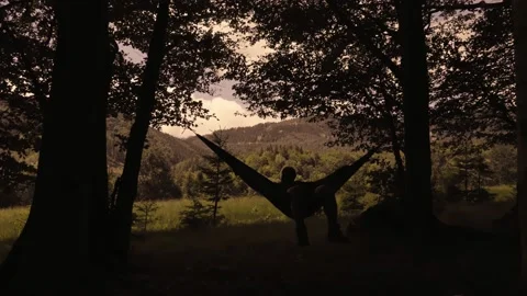 Man relaxing in hammock at sunset in the mountains Stock Footage 133322989
