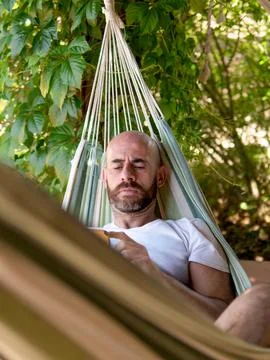 Man Relaxing in Hammock Using Smartphone Stock Photos