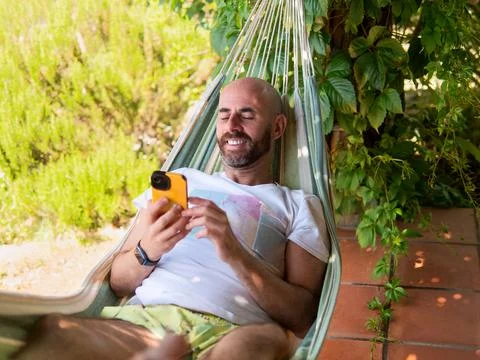 Man Relaxing in Hammock Using Smartphone Stock Photos