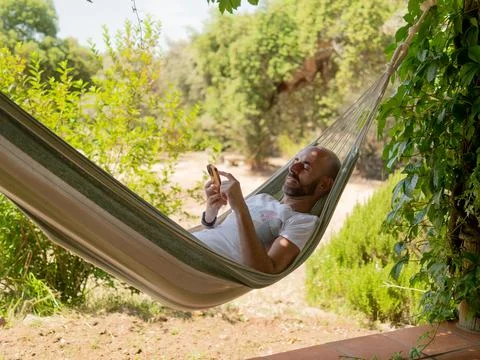Man Relaxing in Hammock Using Smartphone Stock Photos