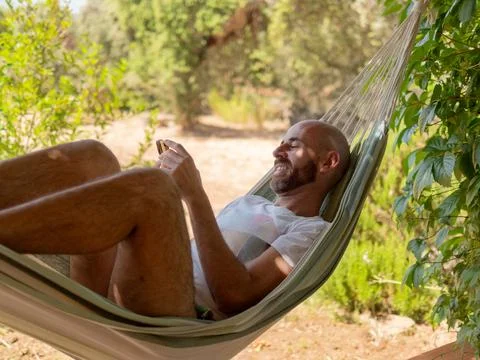 Man Relaxing in Hammock Using Smartphone Stock Photos