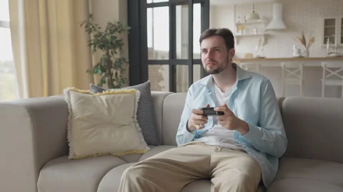 Man Relaxing At Home Playing Console Game With Focused Look In Living Room Stock Footage 311258823