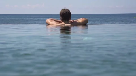 Man relaxing in infinity pool 스톡 동영상 65826703