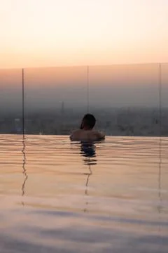 Man relaxing in infinity pool watching muscat sunset Stock Photos