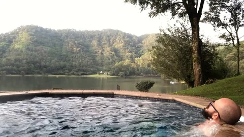 Man relaxing in a jacuzzi with a mountain view Stock Footage 104722494