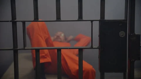 Man relaxing in jail cell through bars | Stock Video | Pond5