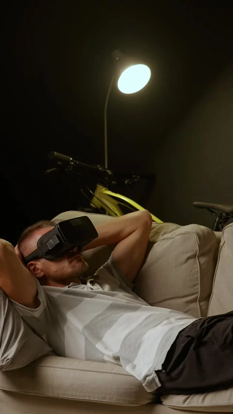 Man relaxing lying on sofa at home wearing Virtual Reality headset. Stock Footage 279843879