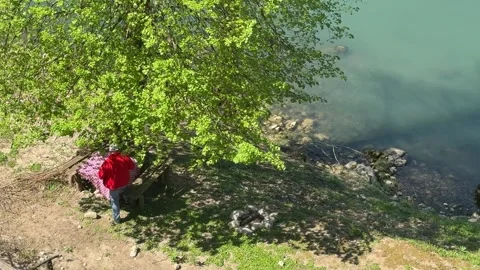 Man Relaxing at Rustic Picnic Table Under Tree Near River, Countryside Slow Livi 動画素材 333523020