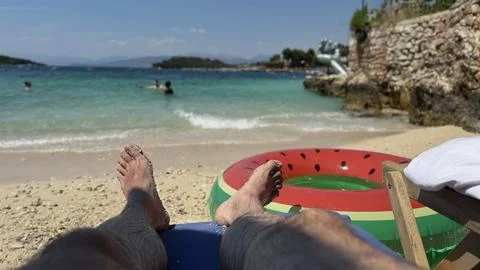 Man relaxing on a sandy beach with an inflatable ring by turquoise sea Stock Photos