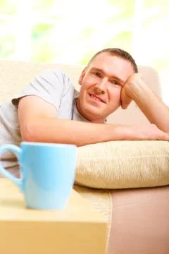 Man relaxing on sofa with cup Stock Photos