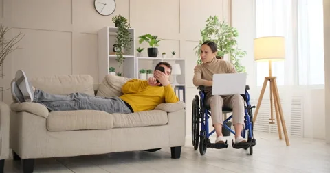 Man relaxing on sofa having discussion with disabled wife over mobile phone Video stock 145205920