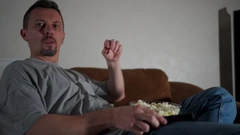 Man Relaxing on Sofa at Night Watching TV with Popcorn. Adult man sitting o.. Video stock 331971126
