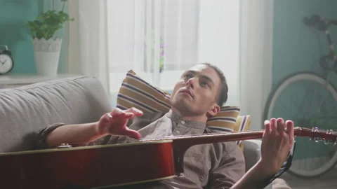 Man Is Relaxing On Sofa Playing Guitar Stock Footage 149262140