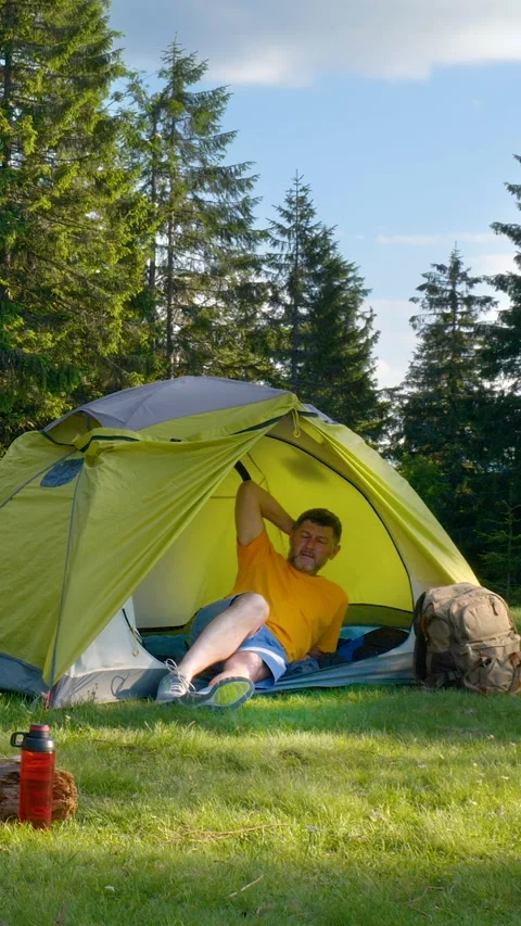 Man relaxing in tent in forest Vidéo 334388653